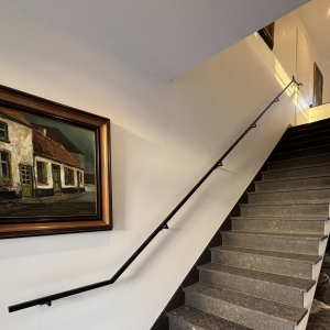 Trapleuning tegen de muur gelakt