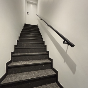 Trapleuning tegen de muur gelakt